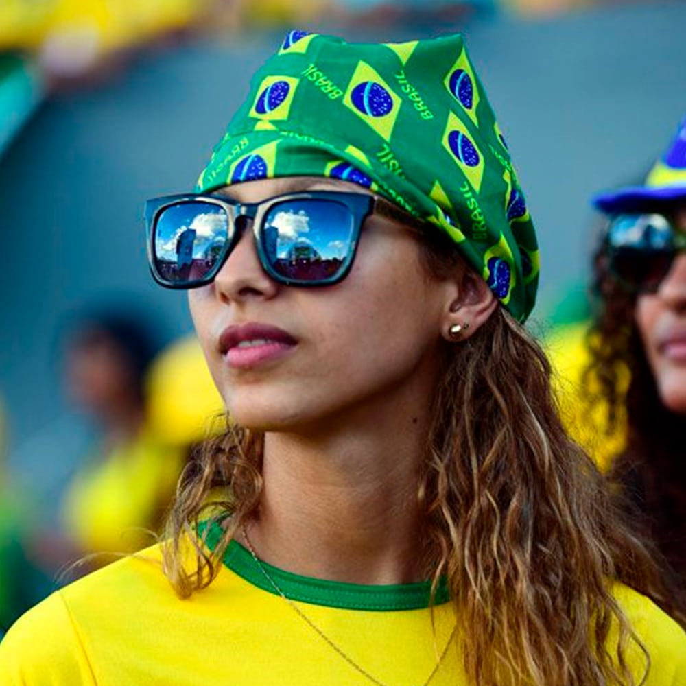 Mulher usando oculos escuro, bandana e camisa da seleção Brasileira