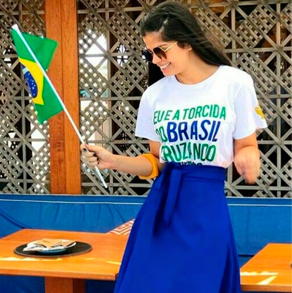 Mulher usando saia azul e segurando a bandeira do Brasil